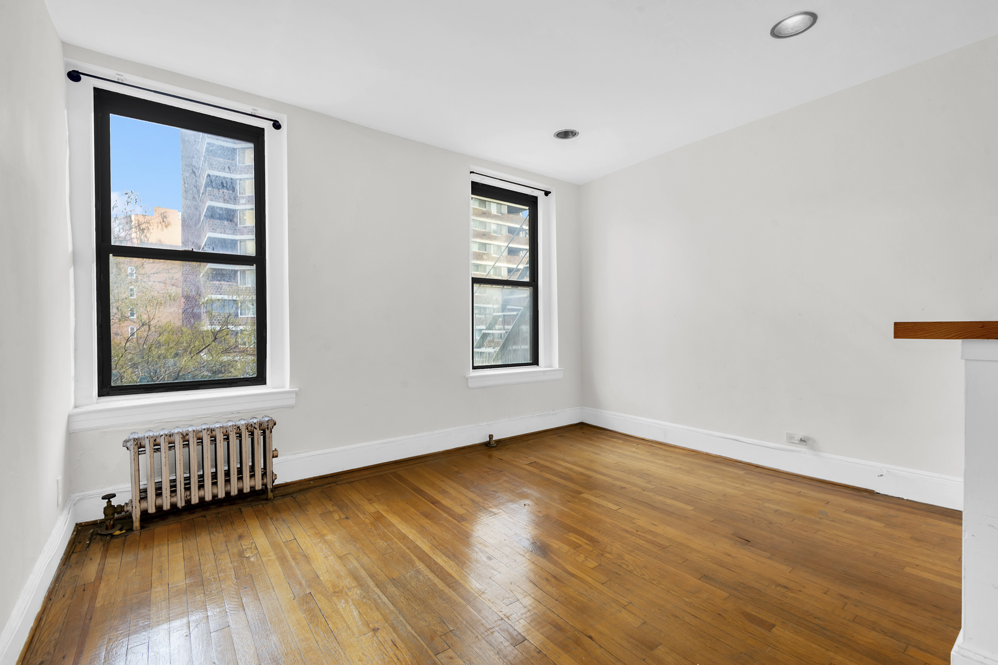 240 East 24th Street, Unit 2E Manhattan, NY 10010 - Photo 6 of 7 an empty room with wooden floor and windows