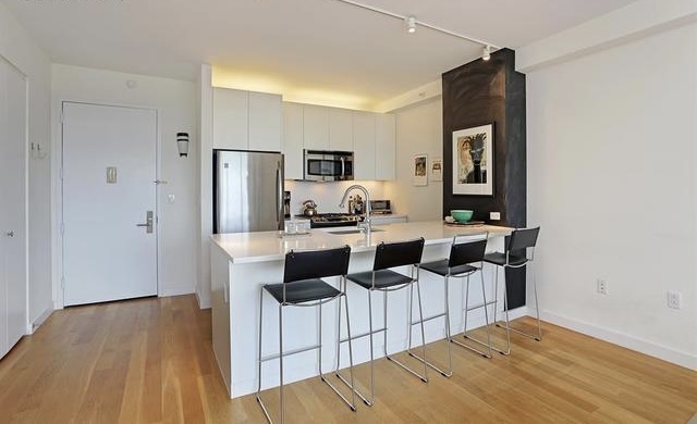 189 Schermerhorn Street, Unit 7D Brooklyn, NY 11201 - Photo 2 of 5 a kitchen with stainless steel appliances kitchen island granite countertop a refrigerator and microwave