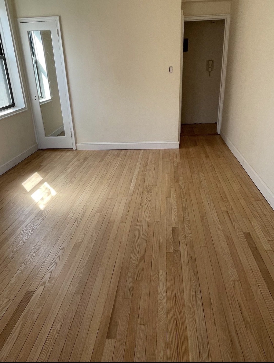 69-40 Yellowstone Boulevard, Unit 510 Queens, NY 11375 - Photo 8 of 11 an empty room with wooden floor and windows