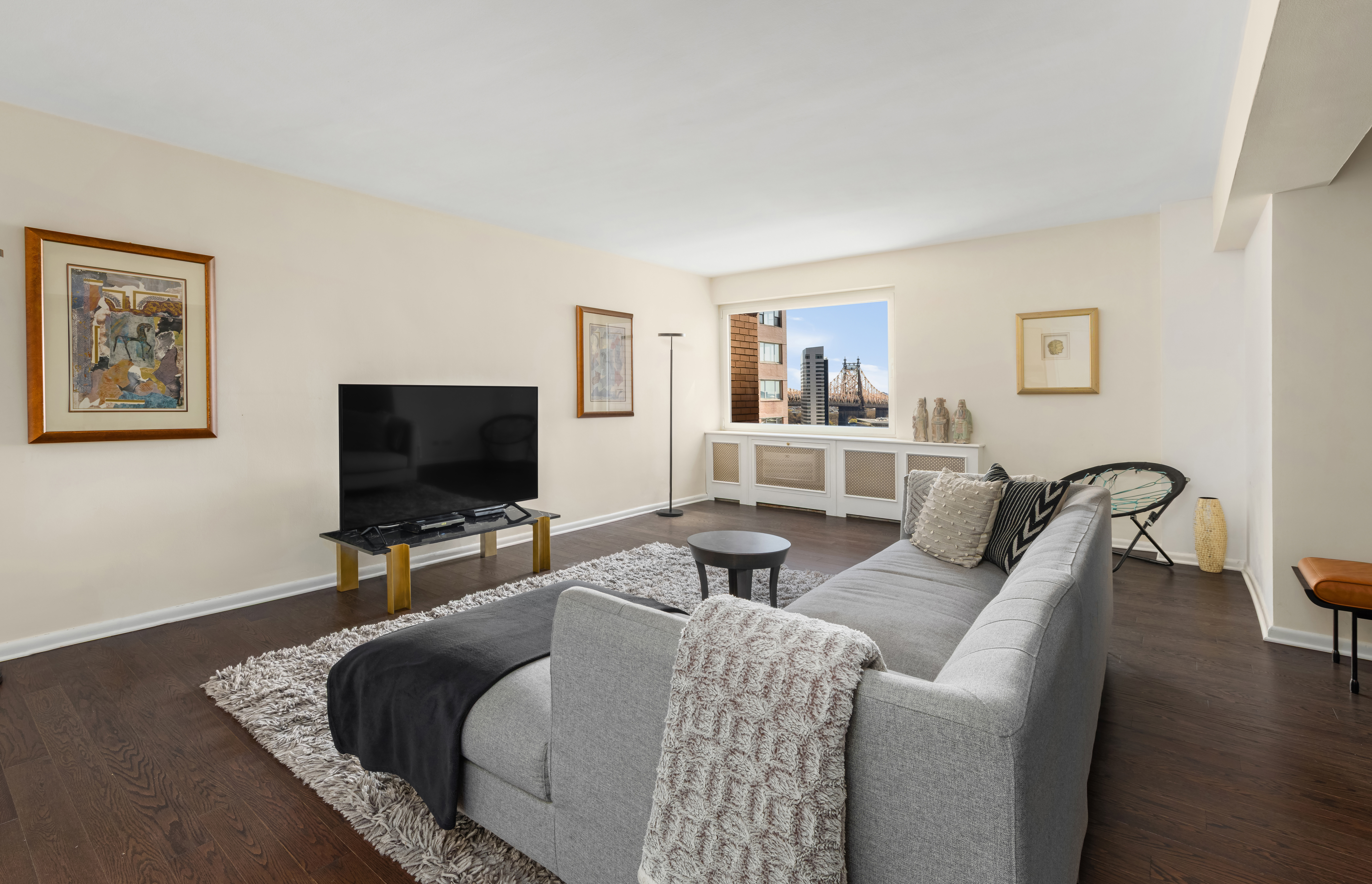 25 Sutton Place South, Unit 18L Manhattan, NY 10022 - Photo 2 of 11 a living room with furniture and a flat screen tv