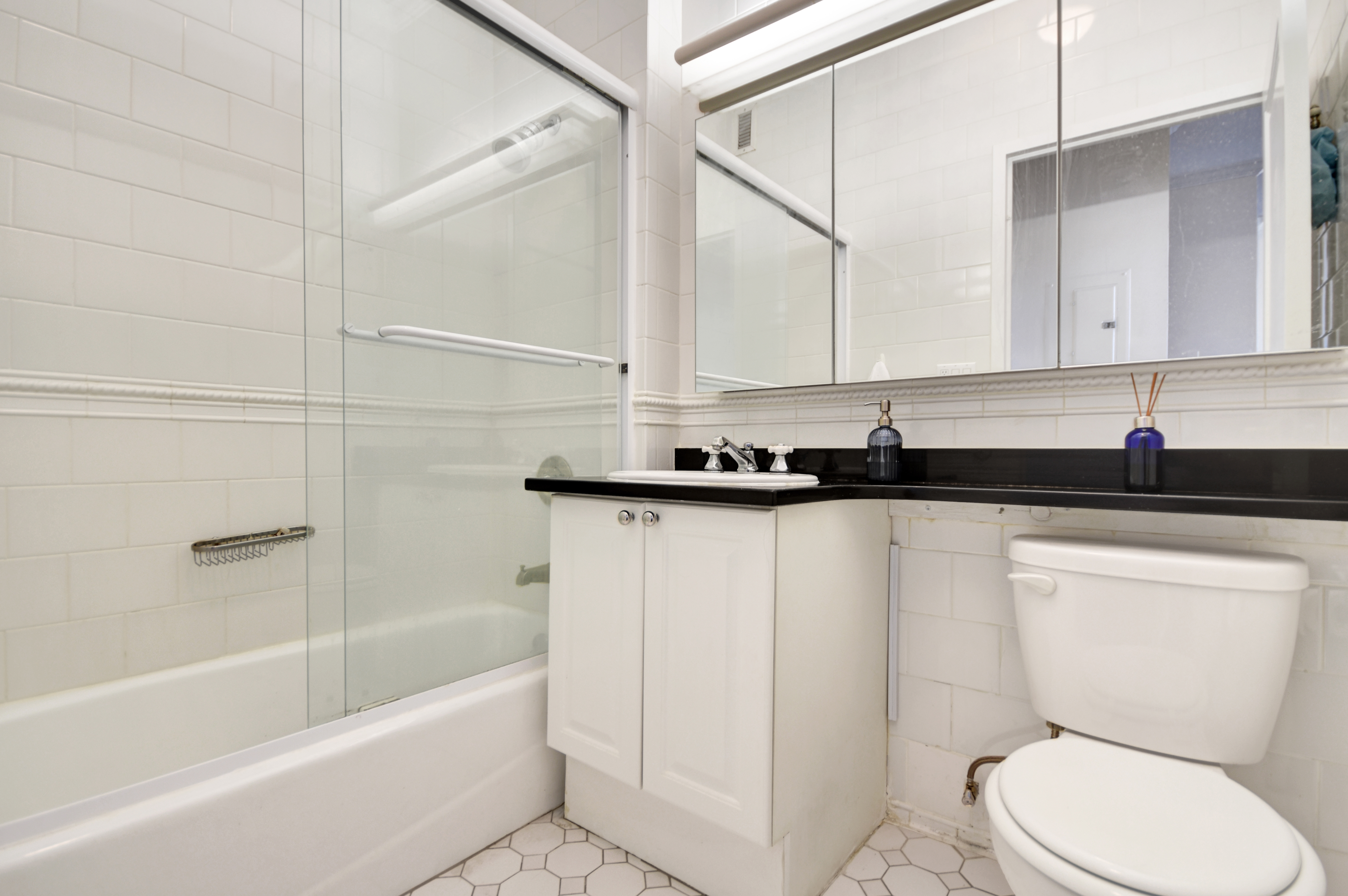 350 East 82nd Street, Unit 11B Manhattan, NY 10028 - Photo 4 of 6 a bathroom with a granite countertop bathtub shower sink and toilet