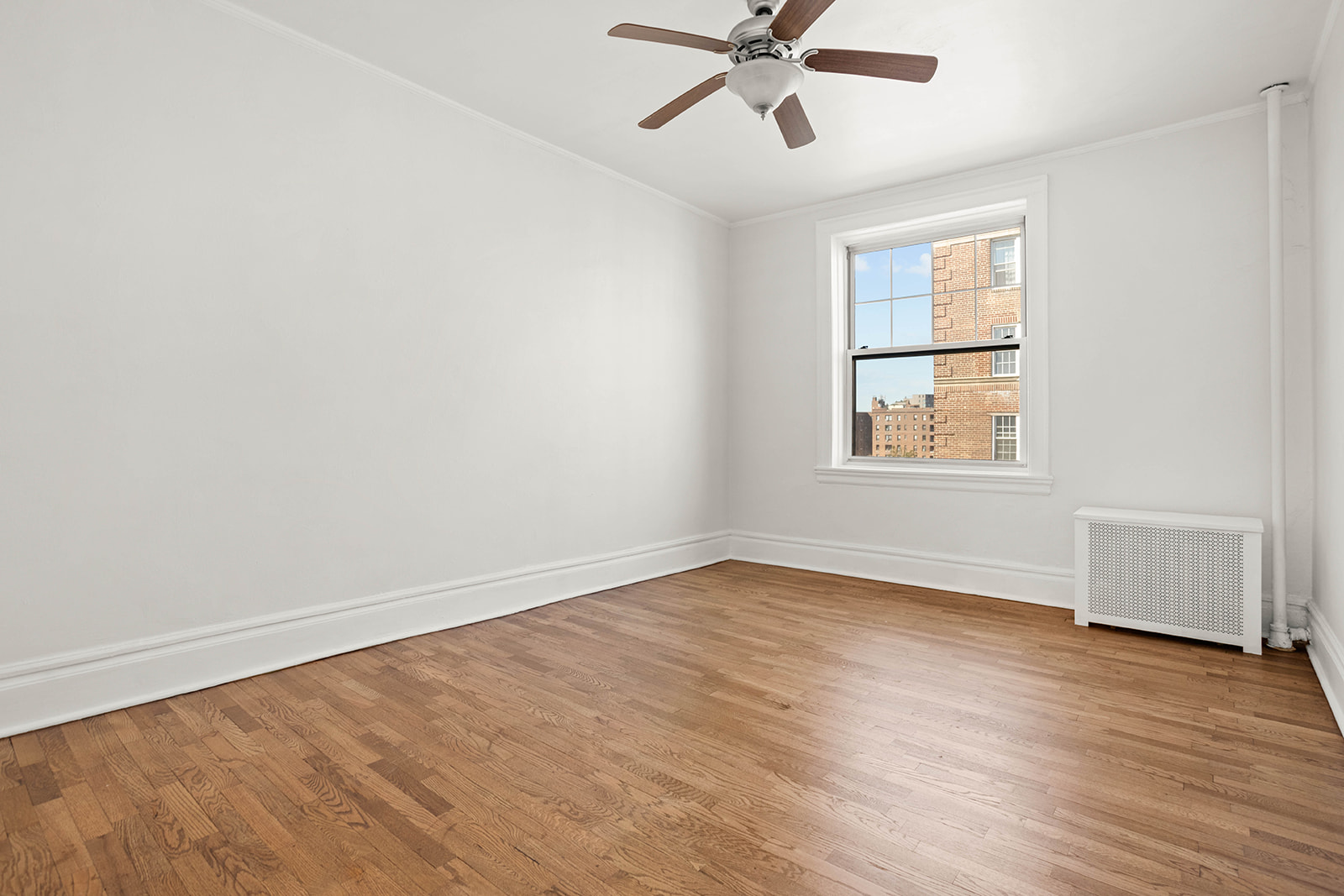 35-55 78th Street, Unit 42 Queens, NY 11372 - Photo 4 of 11 an empty room with wooden floor fan and windows