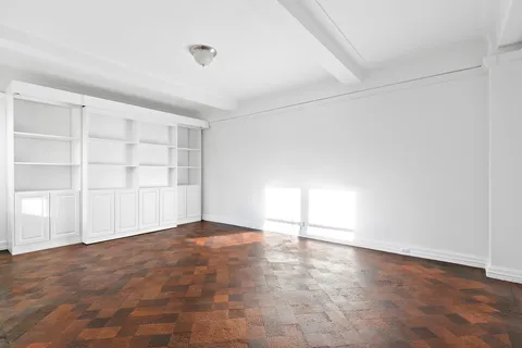 an empty room with cabinet and windows