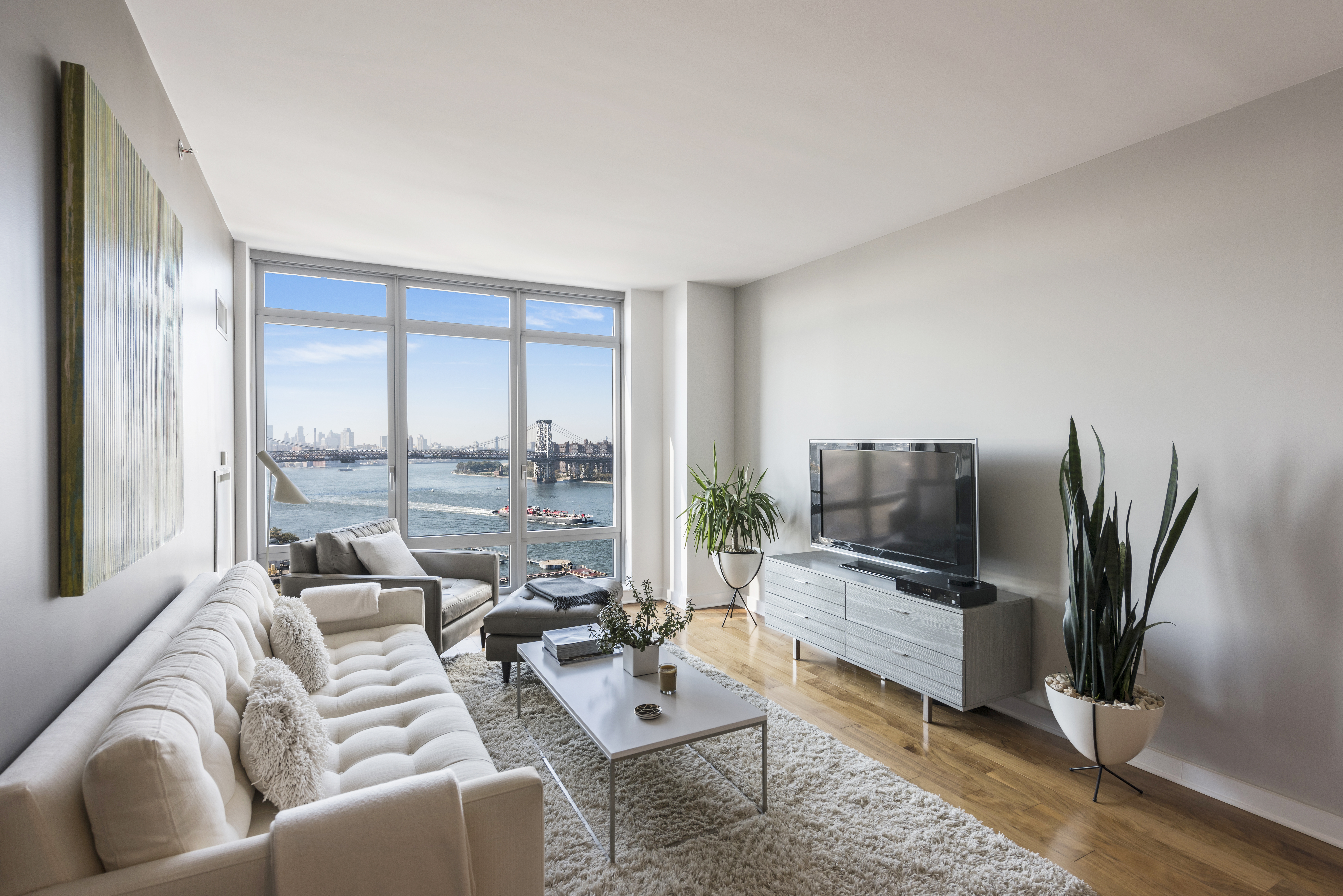 a living room with furniture flat screen tv and large windows