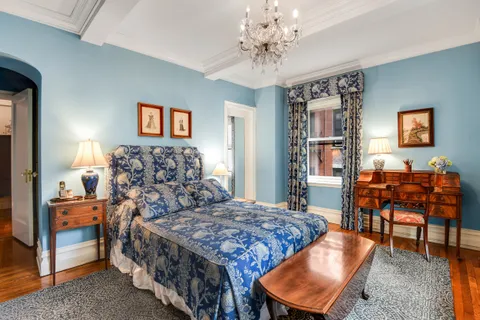 a bedroom with a bed and dresser with chair