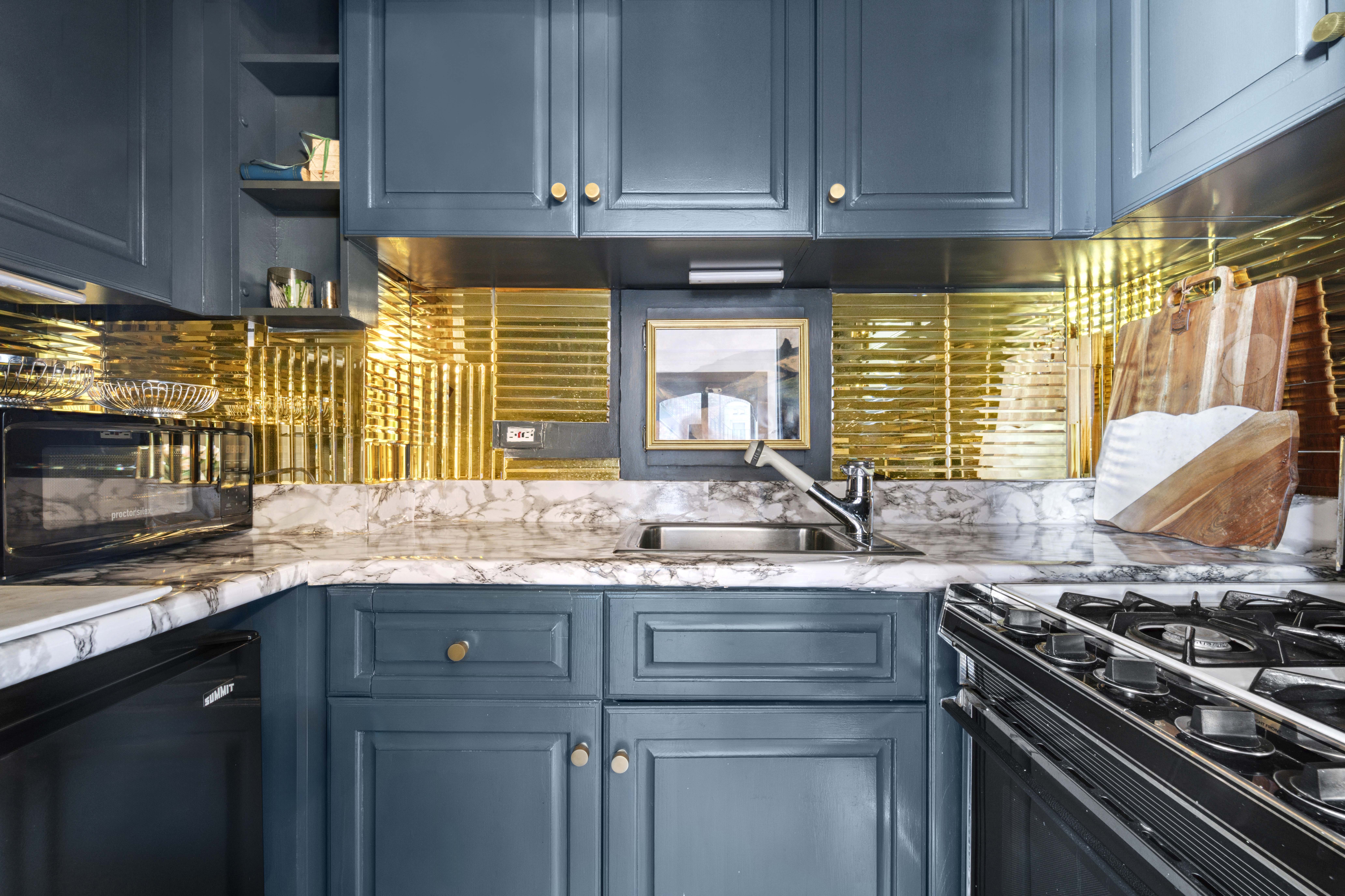 1 West 67th Street, Unit 608 Manhattan, NY 10023 - Photo 6 of 16 a kitchen with stainless steel appliances granite countertop a sink a stove and a microwave
