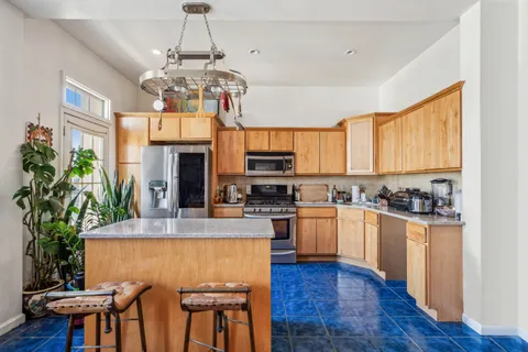 a kitchen with stainless steel appliances granite countertop a stove top oven a sink a dining table and chairs