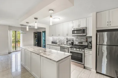 a kitchen with kitchen island granite countertop a stove a sink and a refrigerator