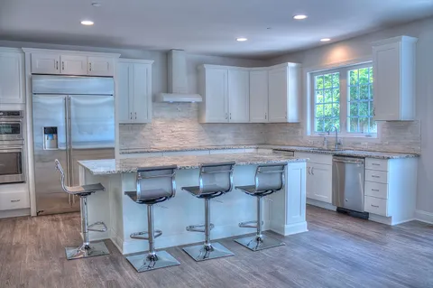 a kitchen with granite countertop a stove a sink a window and wooden cabinets