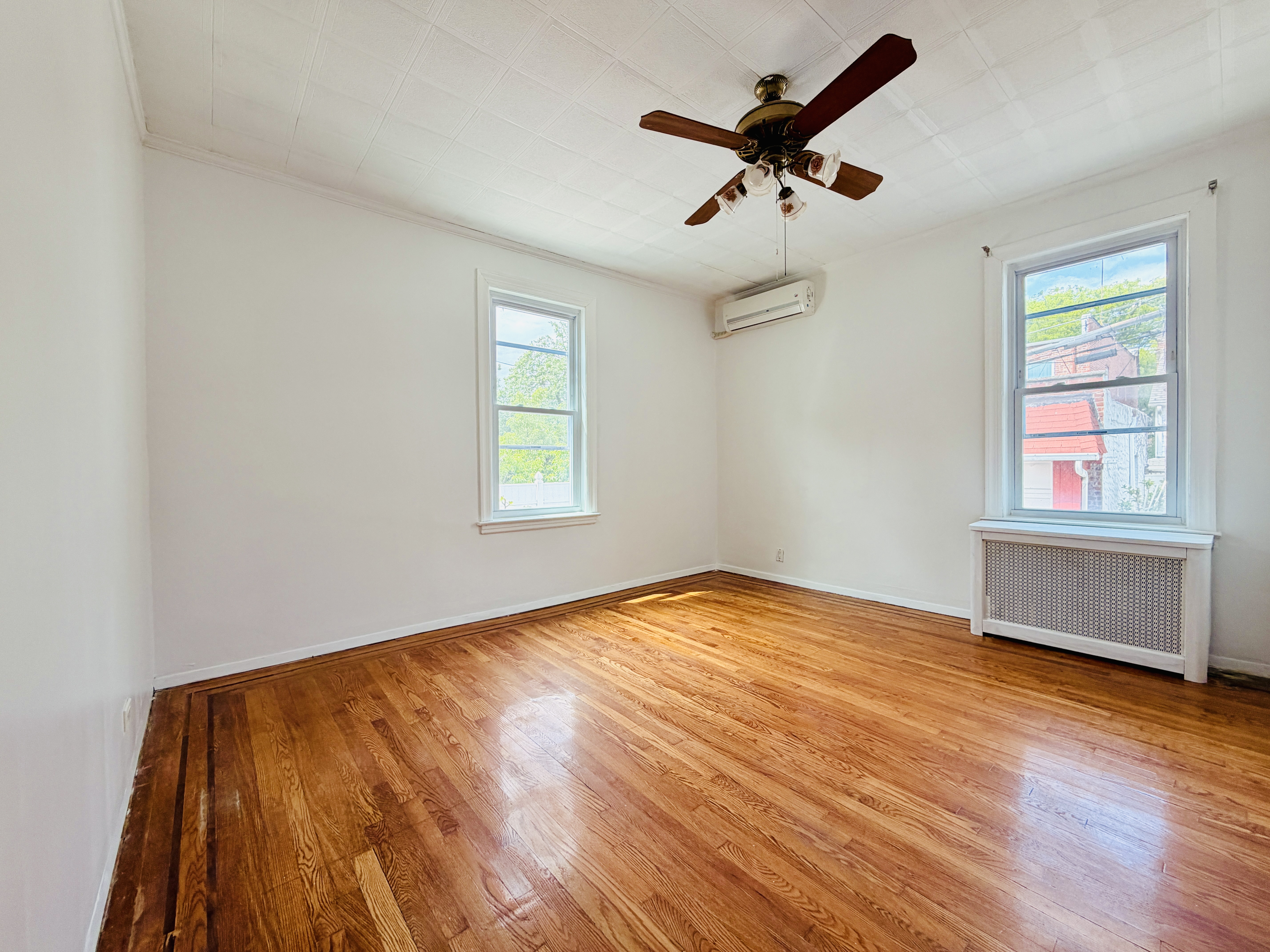 63-33 Haring Street, Unit 1F Queens, NY 11374 - Photo 8 of 13 wooden floor in an empty room with a window