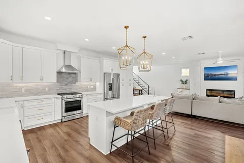 a kitchen with granite countertop a stove a sink a kitchen island with wooden floor and cabinets