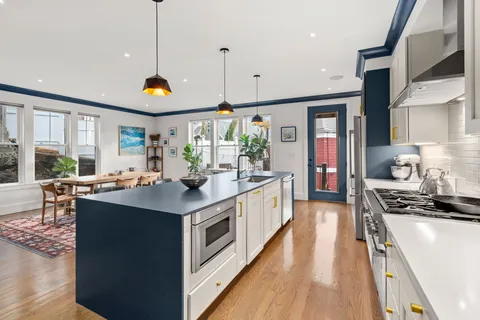 a kitchen with stainless steel appliances granite countertop a stove and a wooden floors
