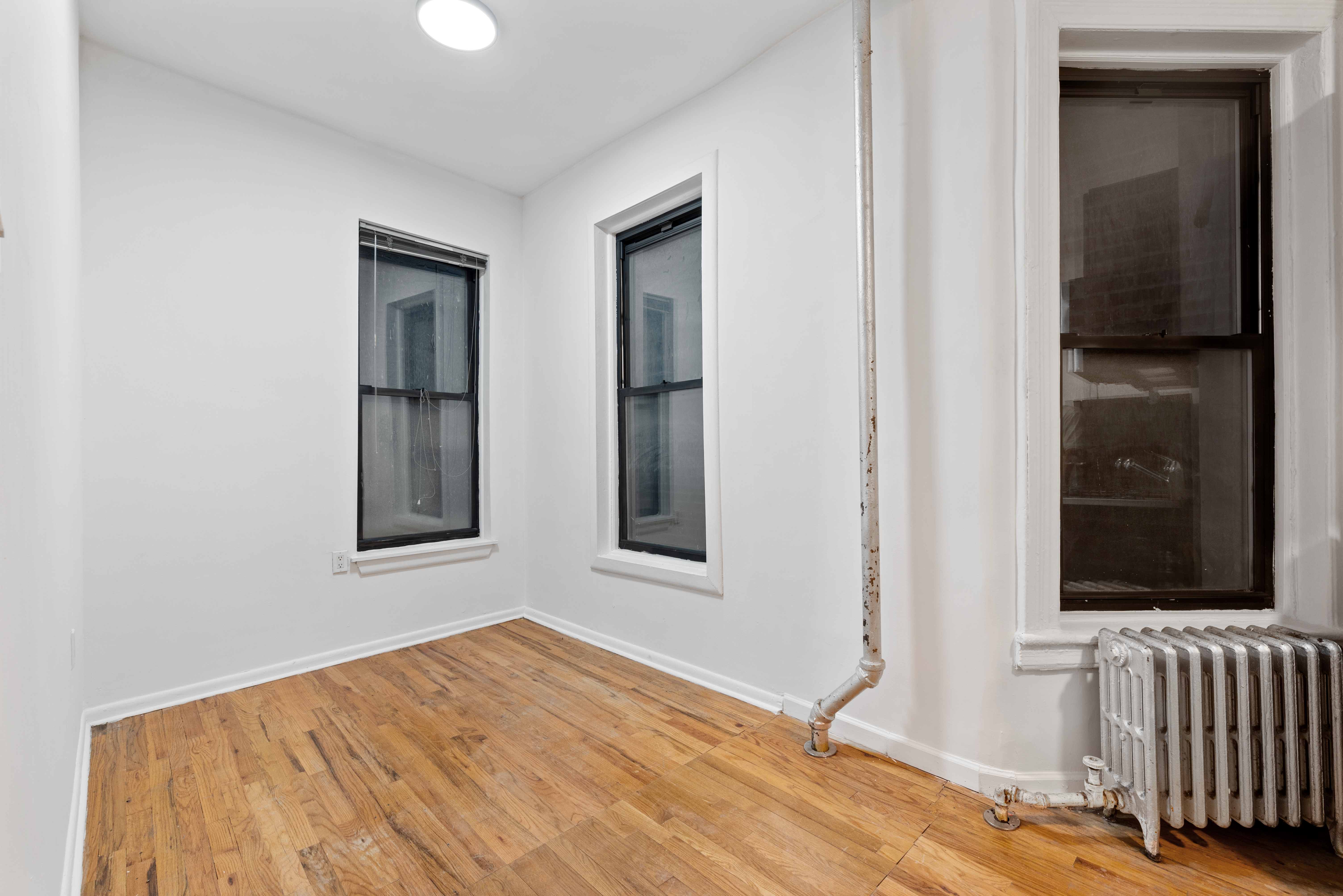 142 Sullivan Street, Unit 18 Manhattan, NY 10012 - Photo 7 of 11 a view of an empty room with wooden floor and a window
