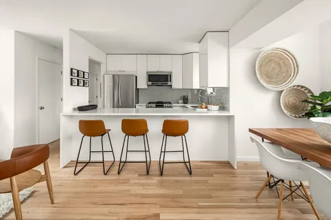 a kitchen with stainless steel appliances granite countertop a table chairs stove and white cabinets