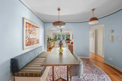 a dining room with wooden floor windows table and chairs