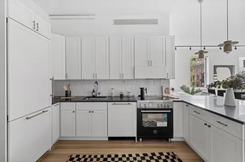 a kitchen with stainless steel appliances a stove a sink and white cabinets