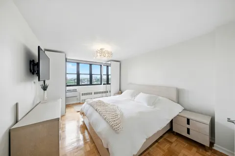 a spacious bedroom with a bed and a flat tv screen on a dresser