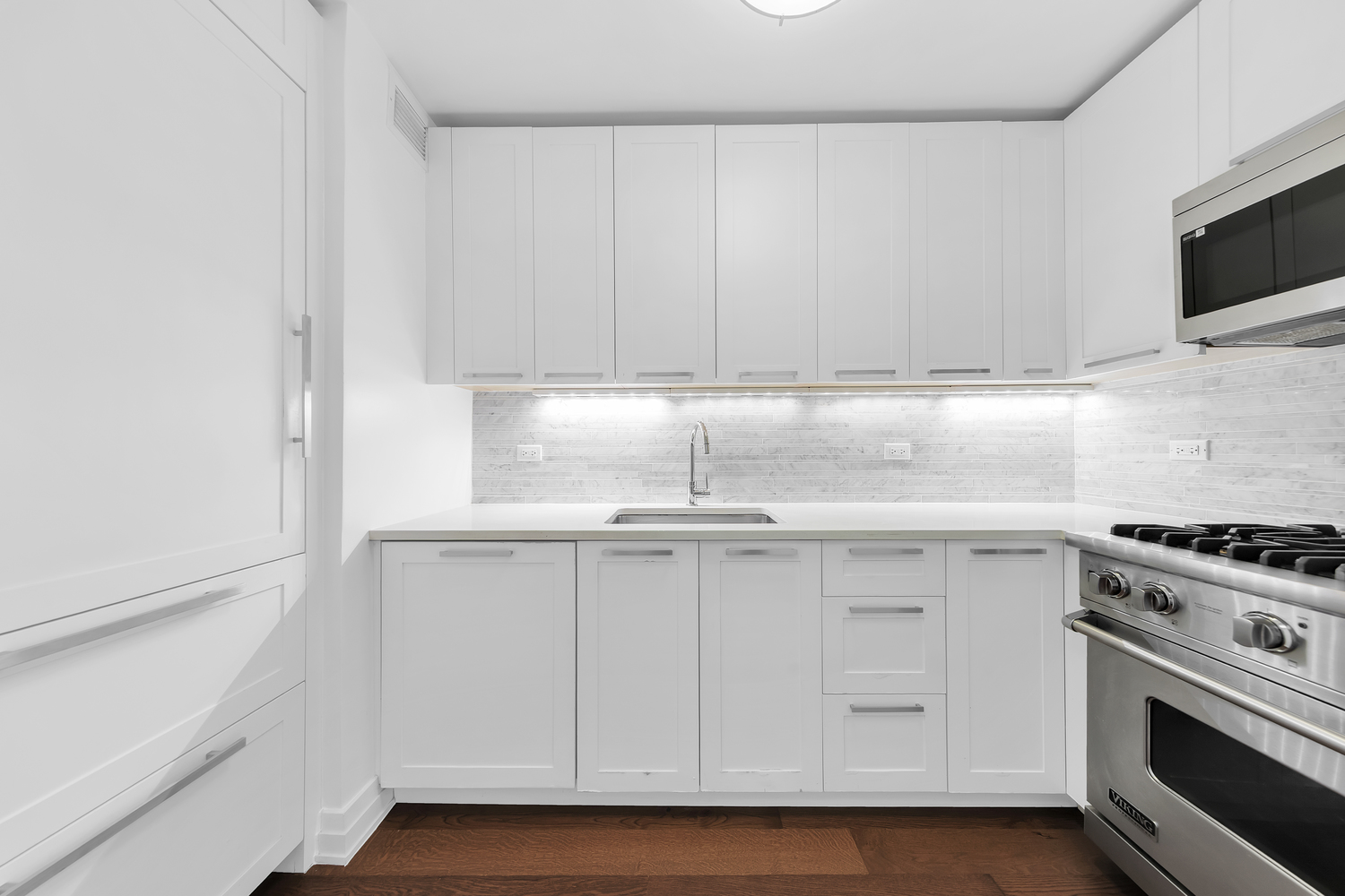200 East 94th Street, Unit 315 Manhattan, NY 10128 - Photo 5 of 25 a kitchen with white cabinets and white appliances