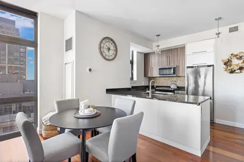 a kitchen with stainless steel appliances granite countertop a dining table chairs and a refrigerator