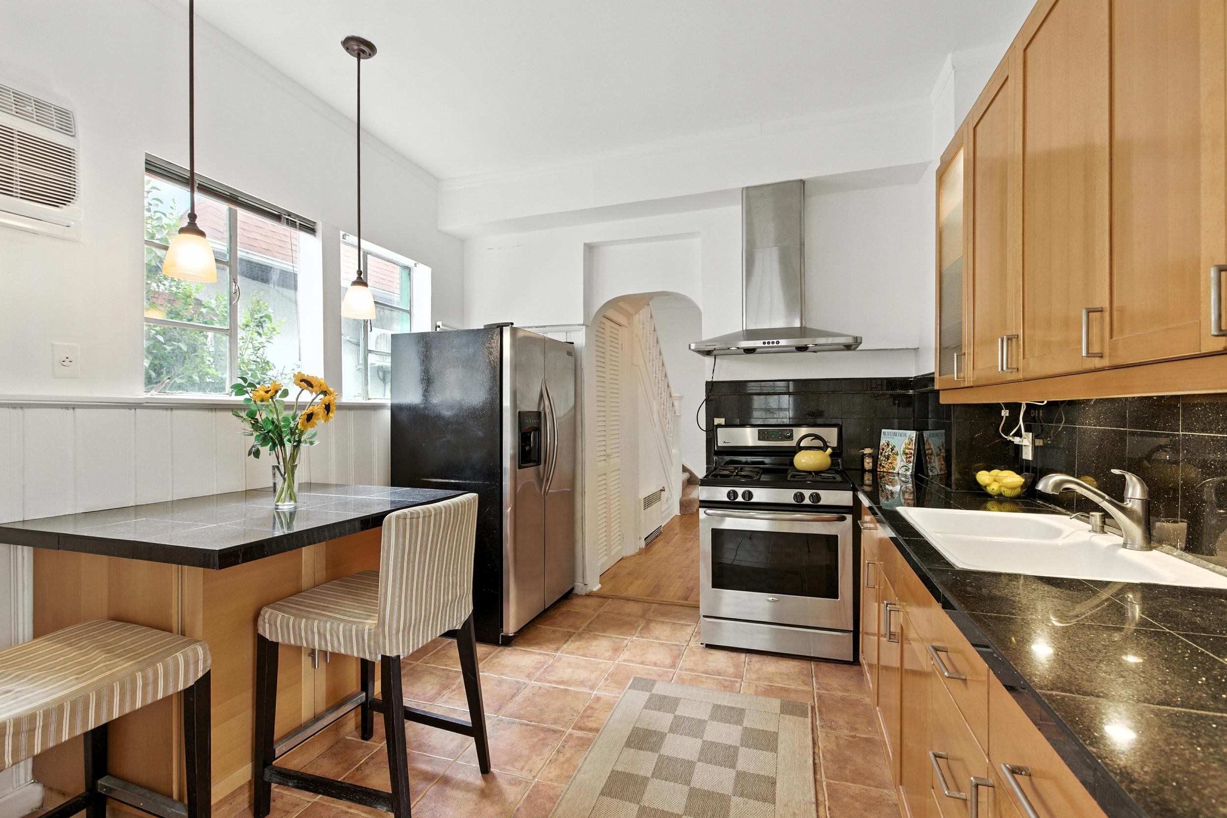 1070 East 13th Street Brooklyn, NY 11230 - Photo 3 of 18 a kitchen with stainless steel appliances granite countertop a stove a refrigerator a sink a stove and chairs with wooden floor