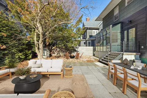 a view of a patio with table and chairs potted plants and large tree