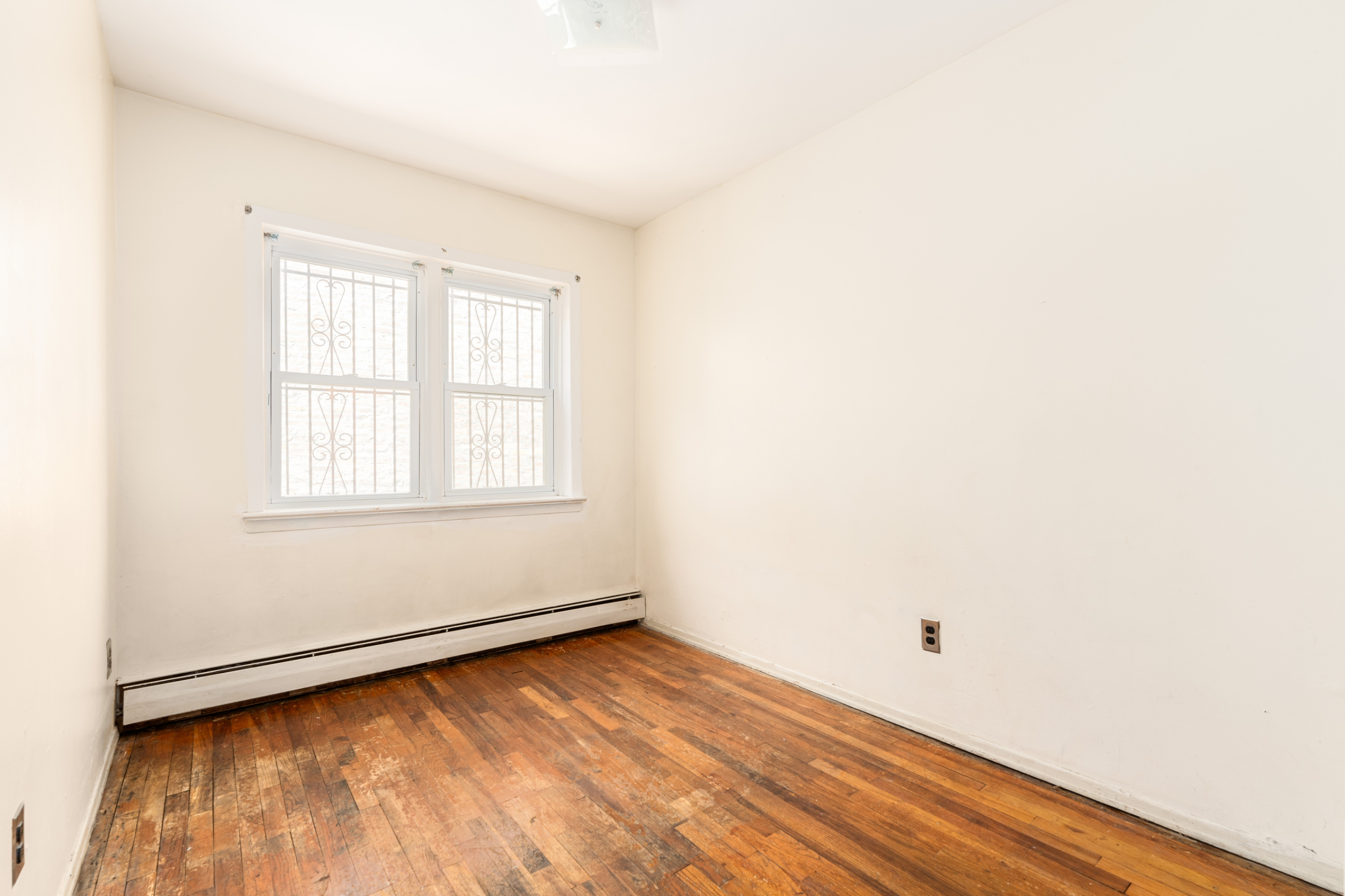 143-11 101st Avenue Queens, NY 11435 - Photo 4 of 9 a view of an empty room with wooden floor and a window