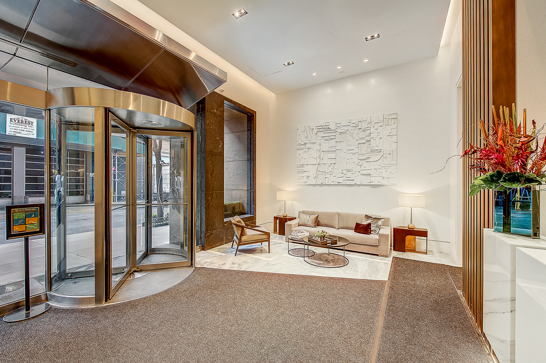 111 West 67th Street, Unit 24L Manhattan, NY 10023 - Photo 6 of 10 a living room with furniture a chandelier and a floor to ceiling window