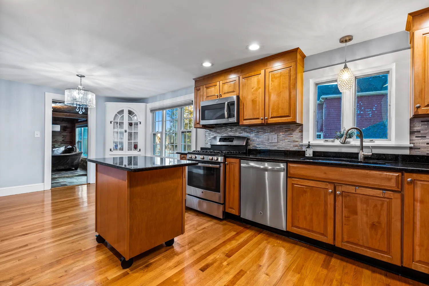 a kitchen with stainless steel appliances granite countertop wooden cabinets a sink a stove a dining table and chairs