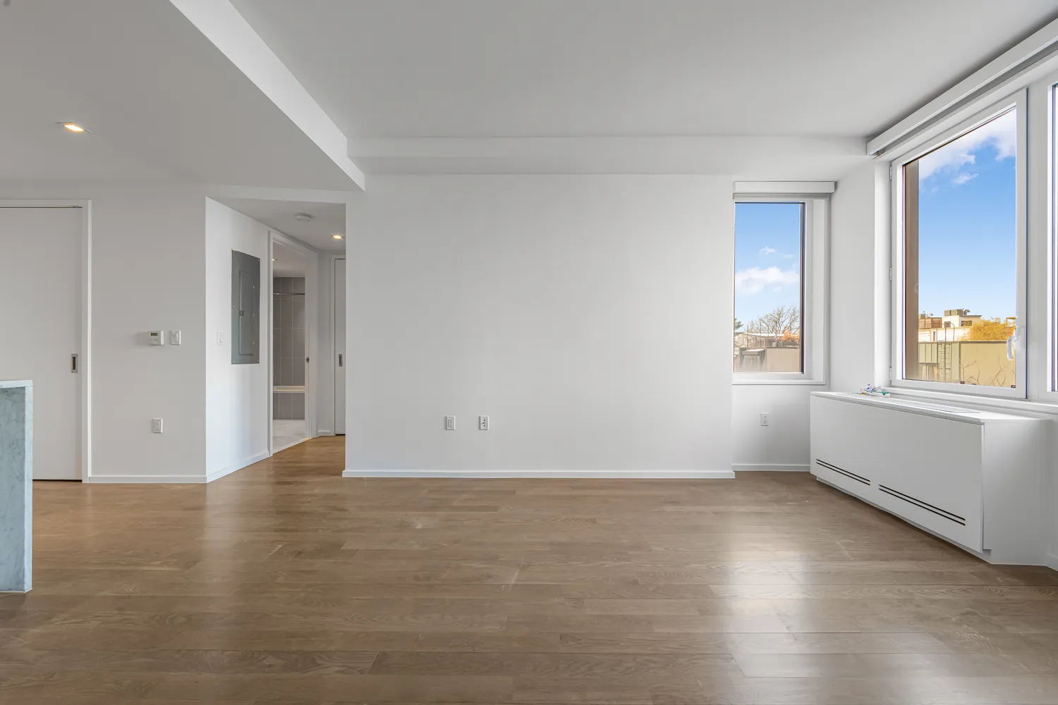 a view of an empty room with wooden floor and a window