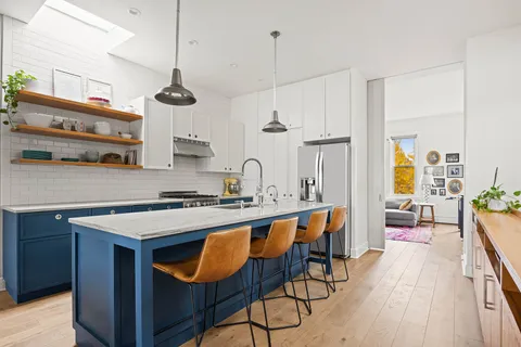 a kitchen with stainless steel appliances a stove a sink a center island and wooden floor
