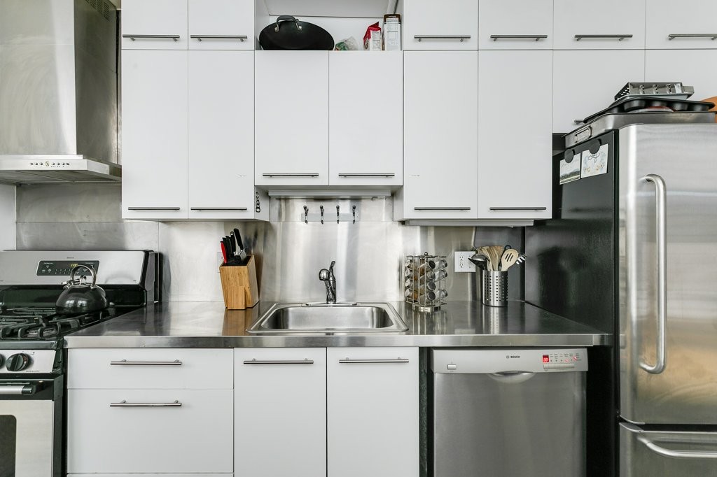 453 Washington Street, Unit 5D Boston, MA 02111 - Photo 16 of 17 a kitchen with stainless steel appliances granite countertop a refrigerator and a sink
