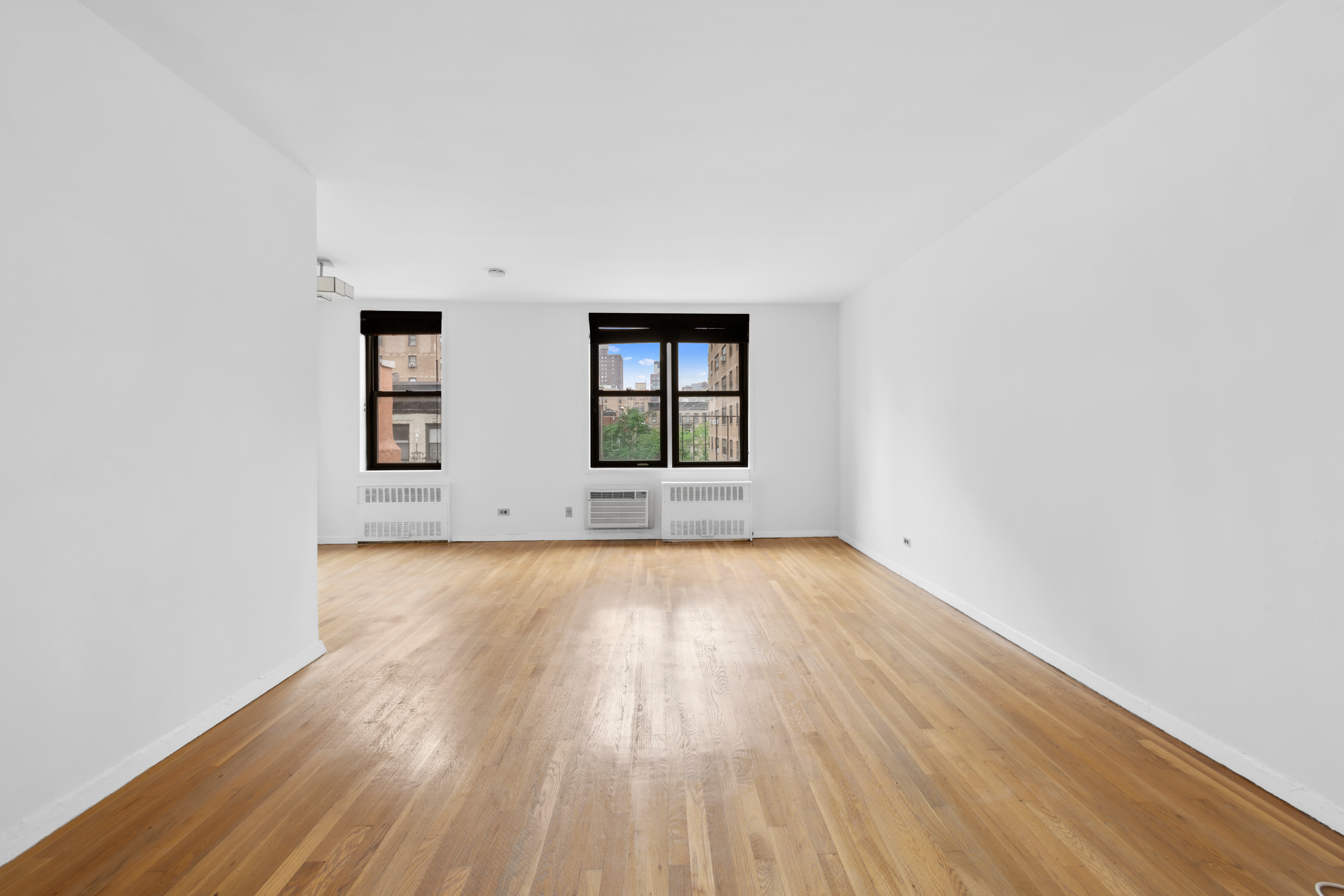 229 East 28th Street, Unit 6D Manhattan, NY 10016 - Photo 2 of 6 an empty room with wooden floor and windows