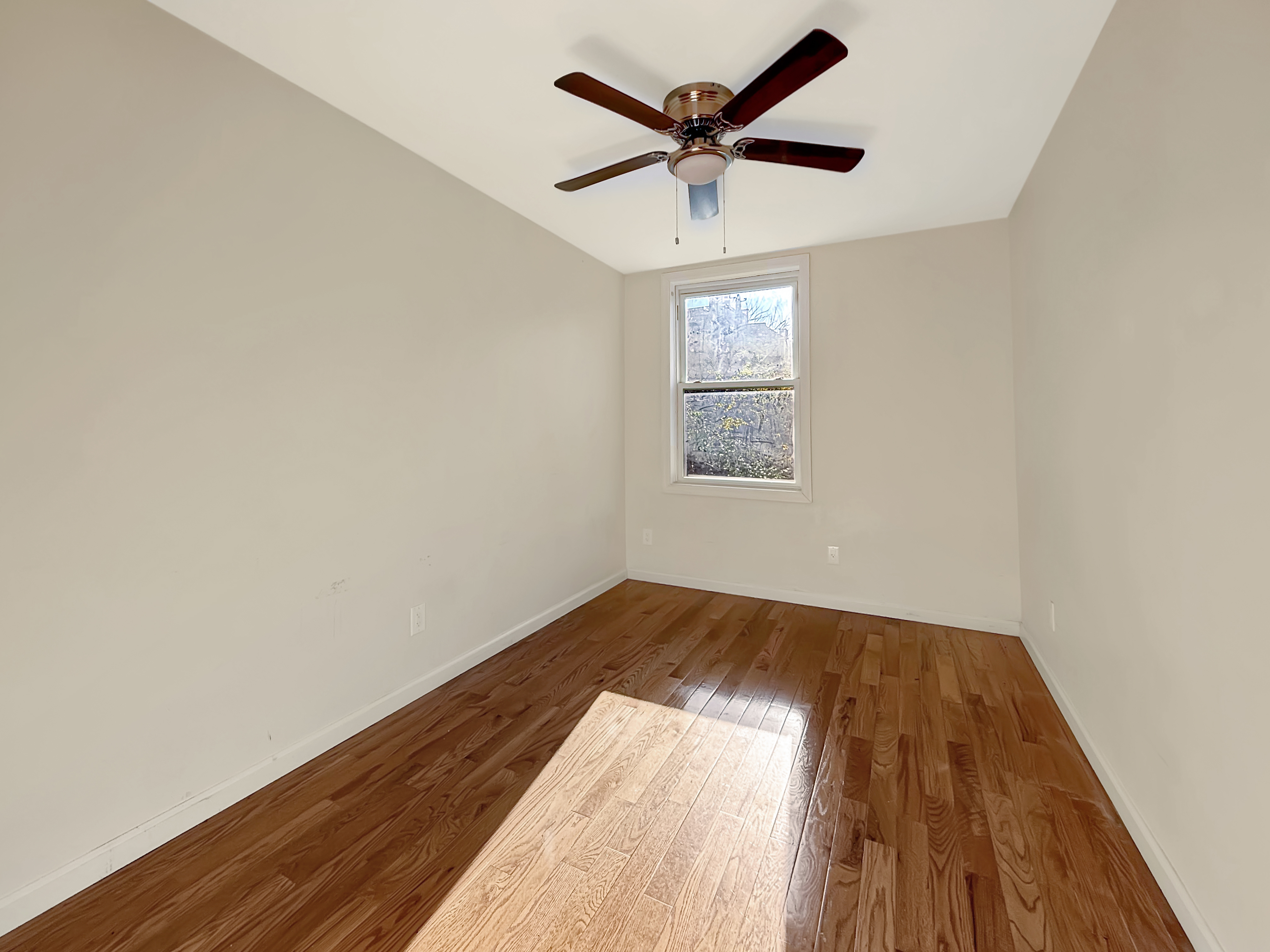 432 Chauncey Street, Unit 1 Brooklyn, NY 11233 - Photo 3 of 9 an empty room with a chandelier fan and windows