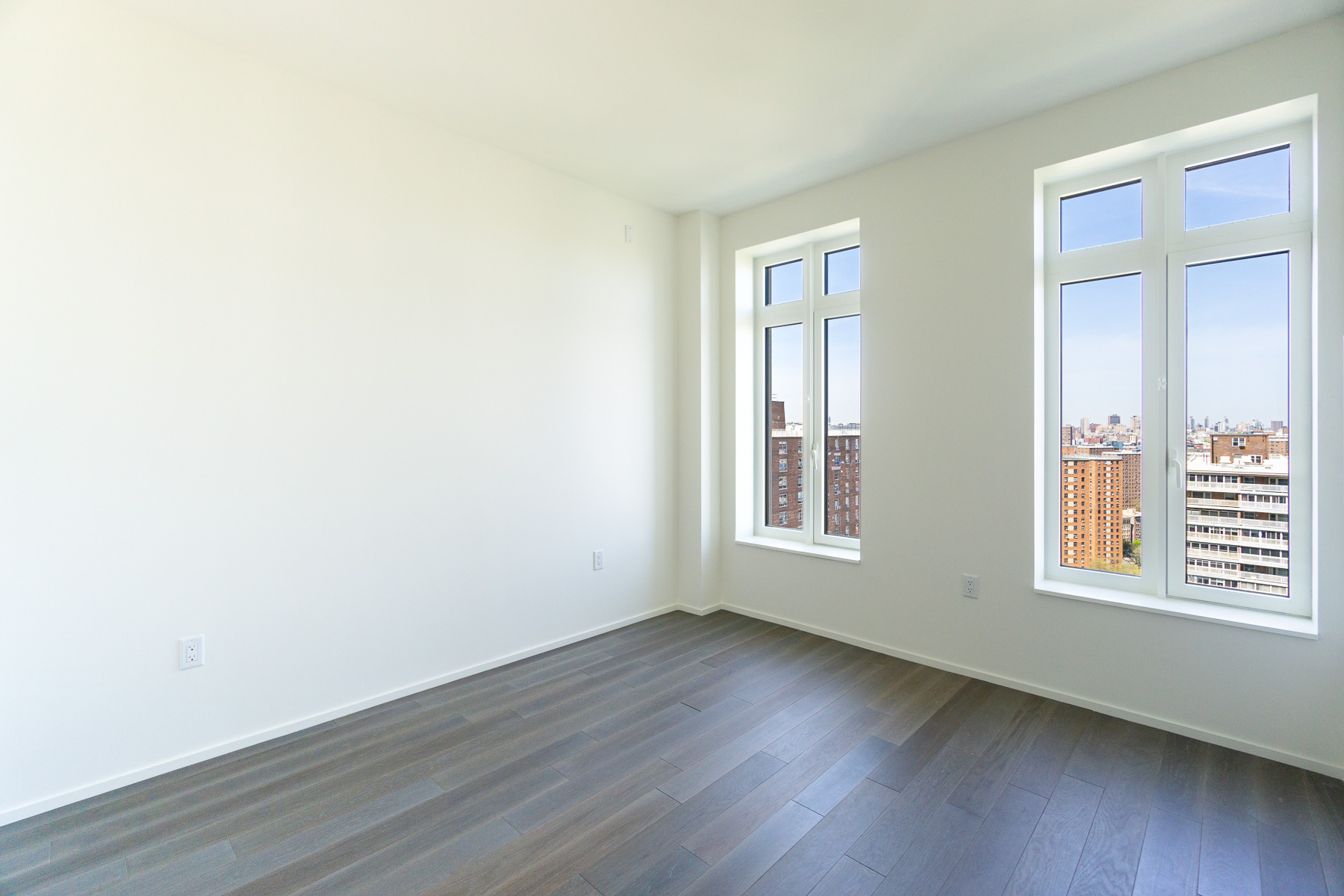 543 West 122nd Street, Unit 17C Manhattan, NY 10027 - Photo 5 of 10 an empty room with wooden floor and windows