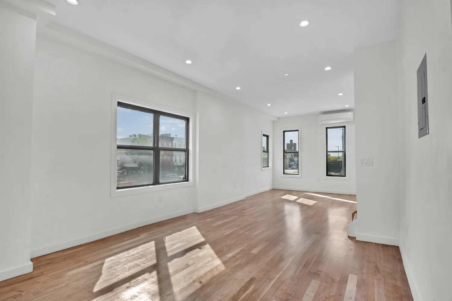 a view of an empty room with wooden floor and a window