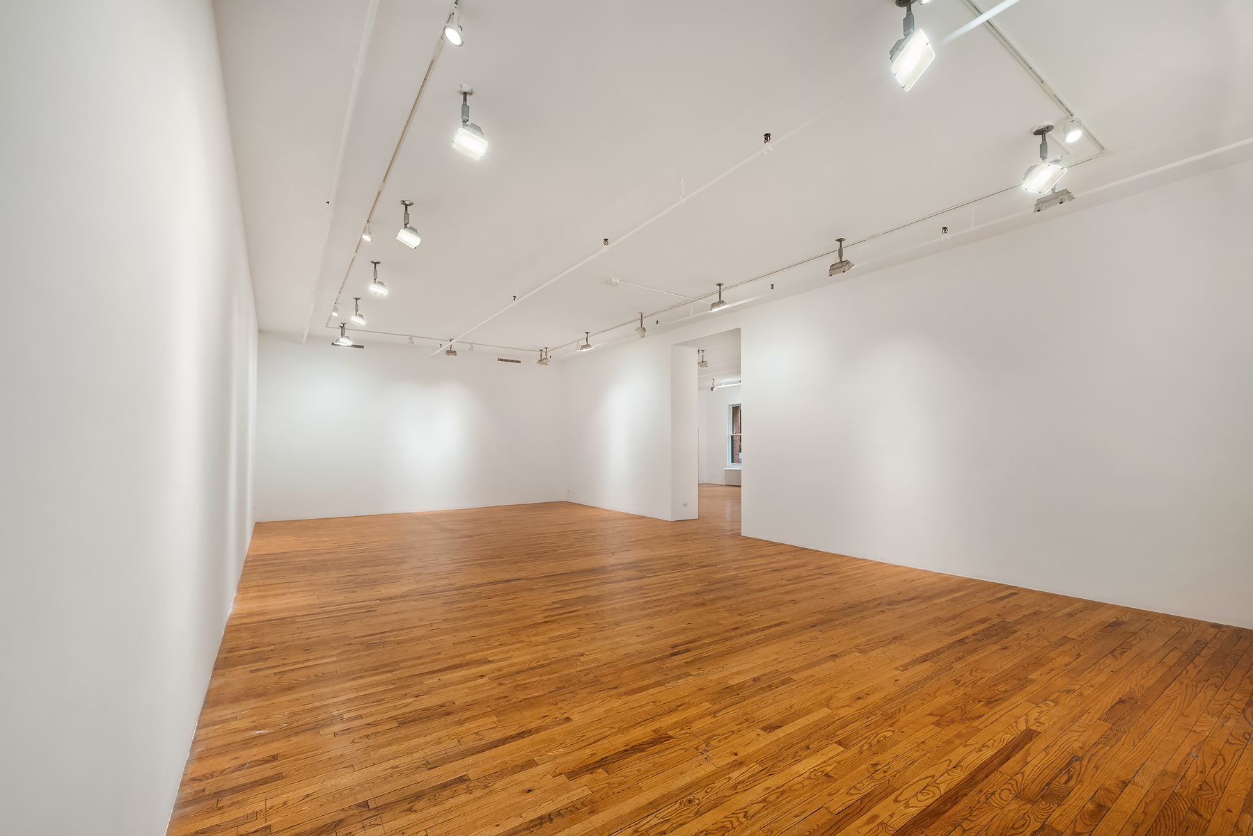 59 Wooster Street Manhattan, NY 10012 - Photo 7 of 10 an empty room with kitchen view and wooden floor