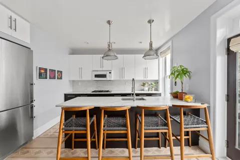 a kitchen with stainless steel appliances granite countertop a stove a refrigerator white cabinets a dining table and chairs