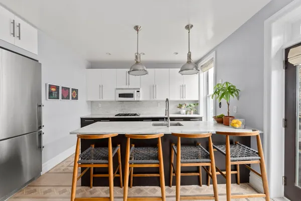 a kitchen with stainless steel appliances granite countertop a stove a refrigerator white cabinets a dining table and chairs