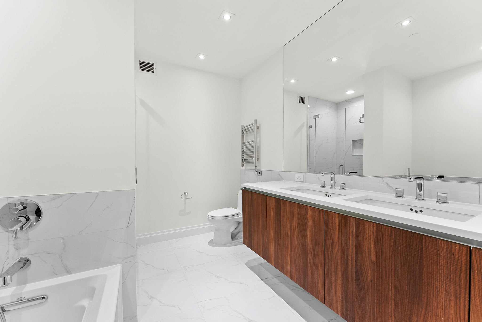 845 United Nations Plaza, Unit 63D Manhattan, NY 10017 - Photo 7 of 16 a large bathroom with a double vanity sink toilet and a tub