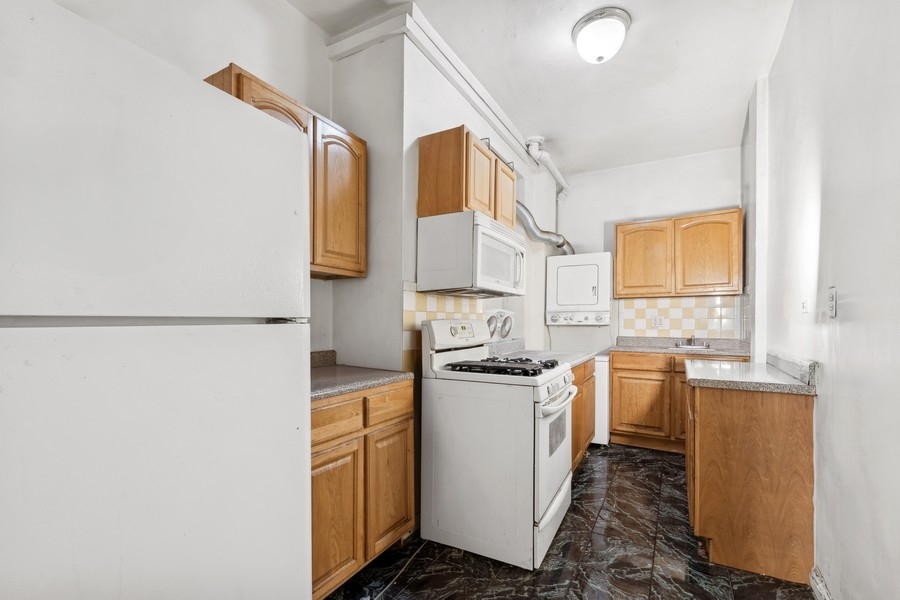 544 West 157th Street, Unit 1 Manhattan, NY 10032 - Photo 4 of 8 a kitchen with stainless steel appliances granite countertop a sink and cabinets