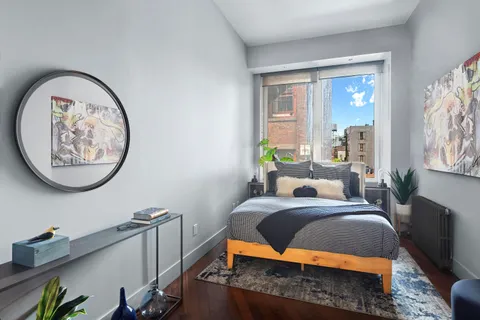 a bedroom with a bed a mirror and a window