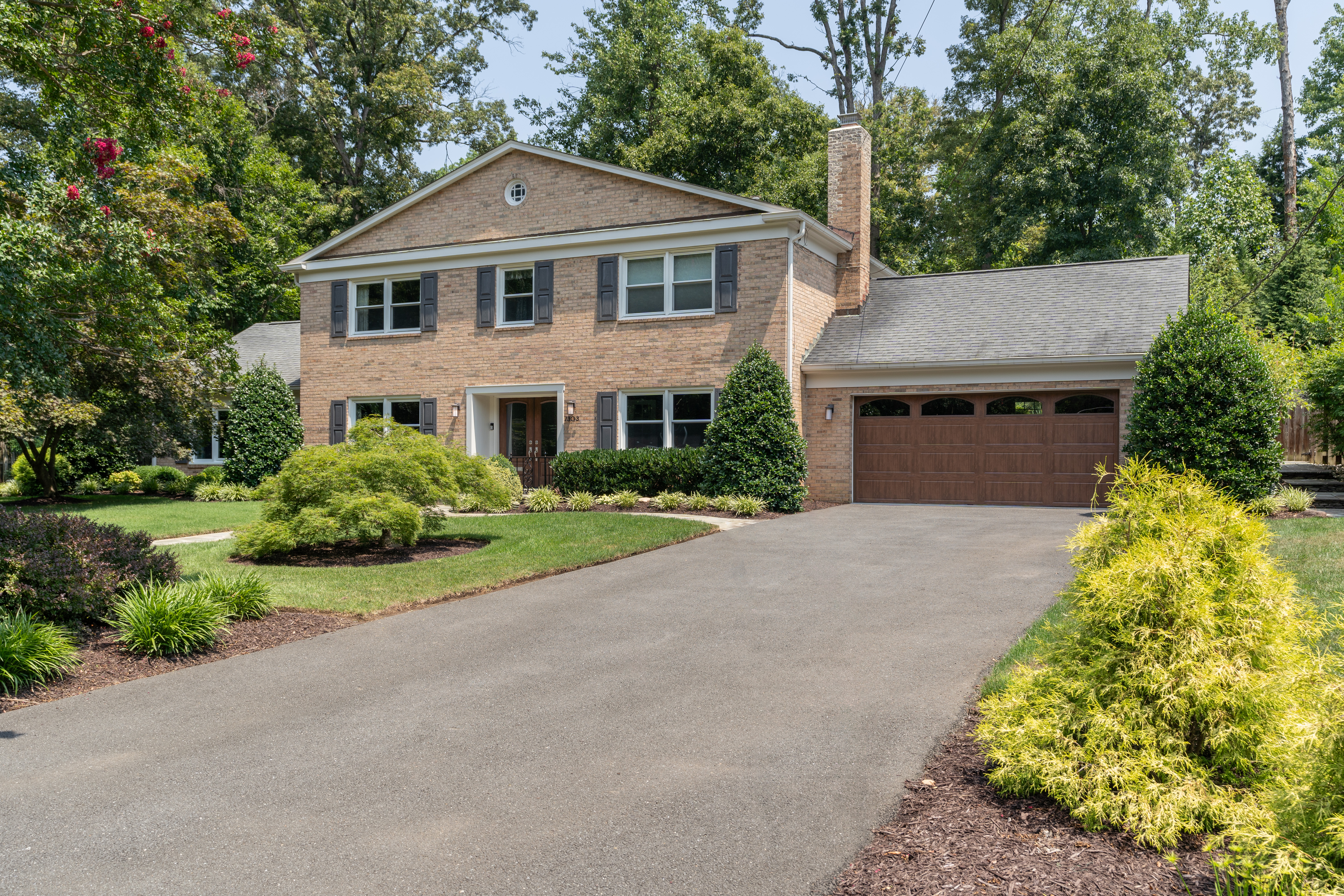 7303 Fort Hunt Road Alexandria, VA 22307 - Photo 2 of 11 a front view of a house with a garden and trees