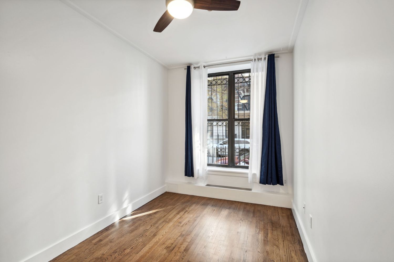an empty room with wooden floor chandelier fan and windows