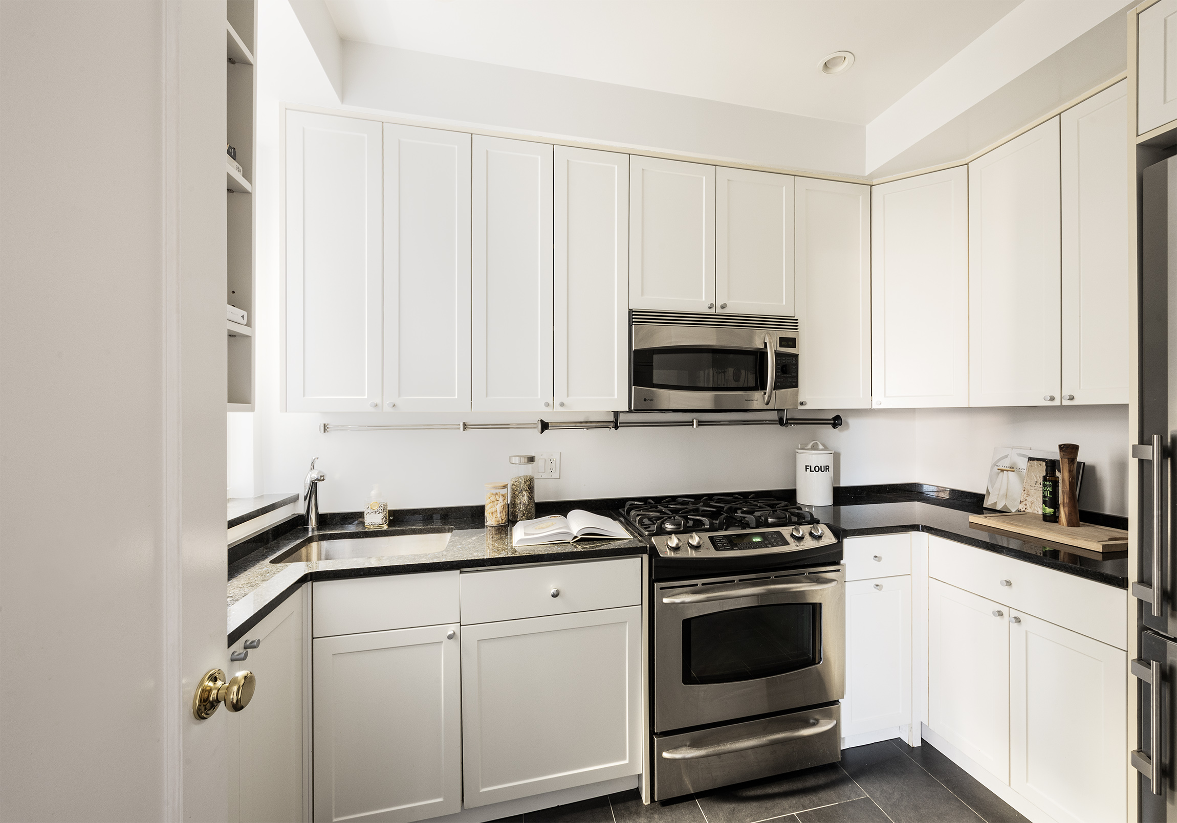 25 5th Avenue, Unit 8F Manhattan, NY 10003 - Photo 5 of 7 a kitchen with white cabinets and black appliances