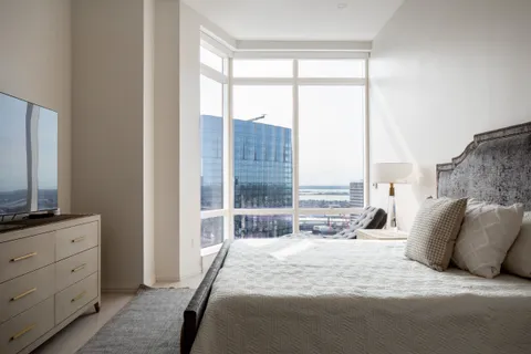 a bedroom with a large window and a balcony