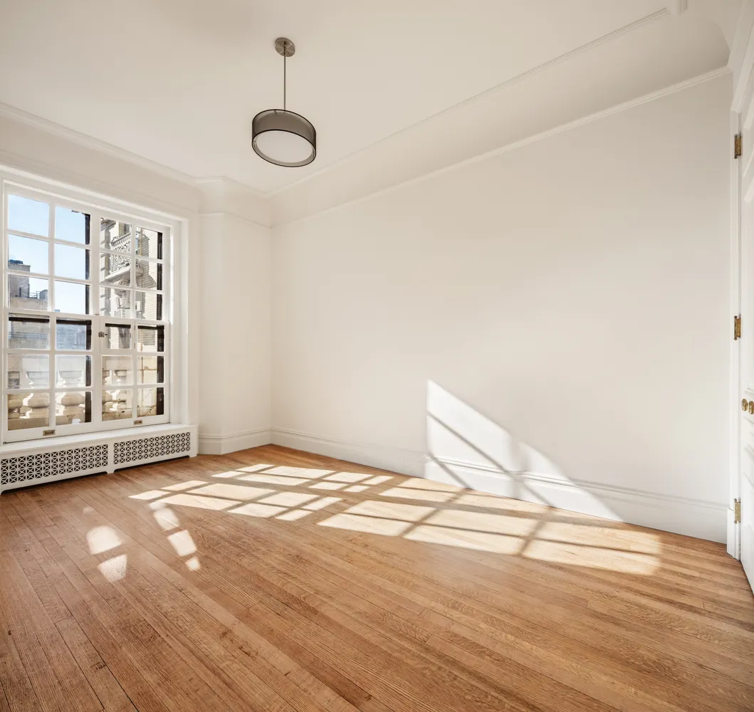 a view of an empty room with window and wooden floor
