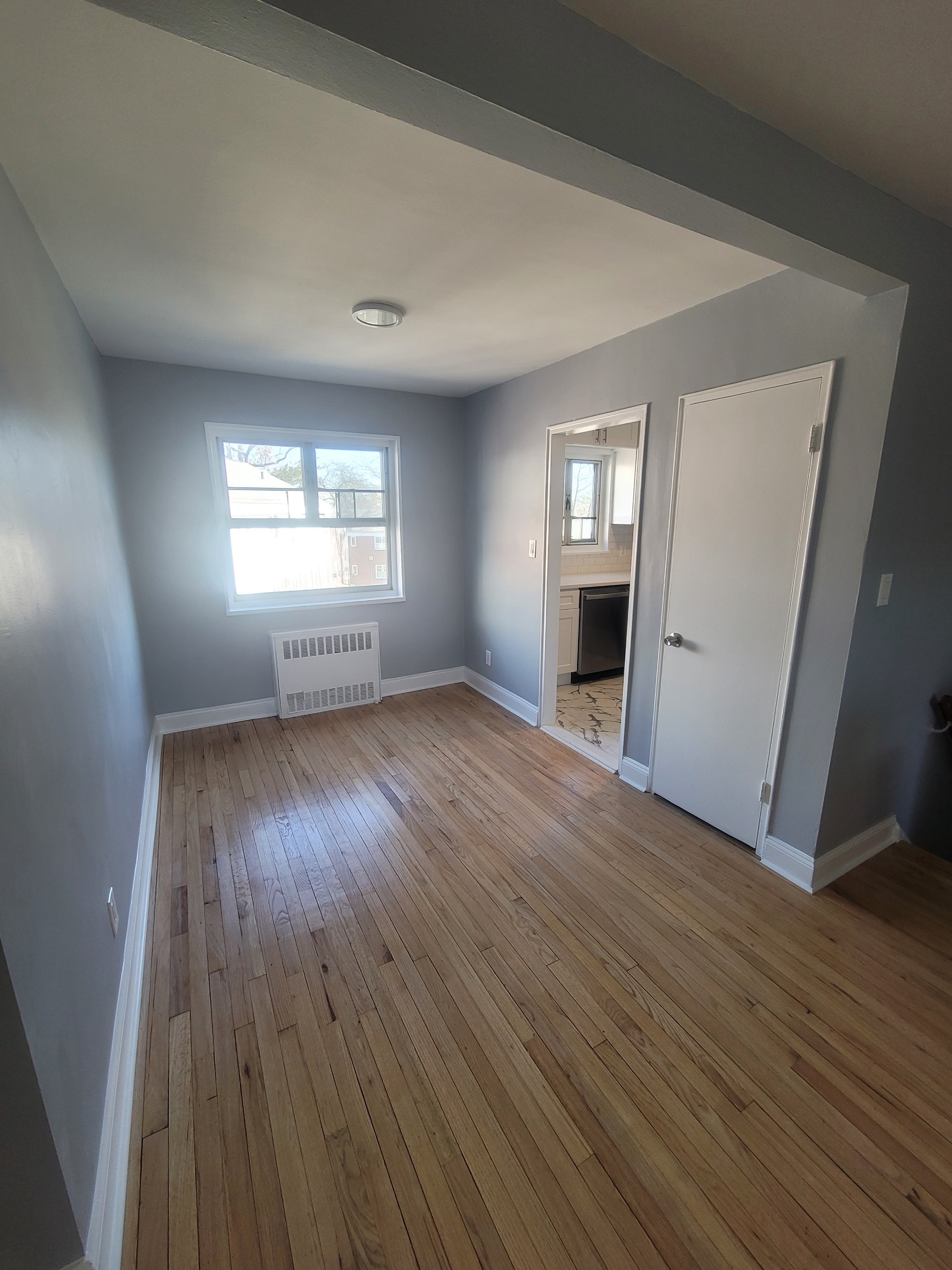 224-24 Manor Road, Unit U Queens, NY 11427 - Photo 6 of 10 an empty room with wooden floor fireplace and windows