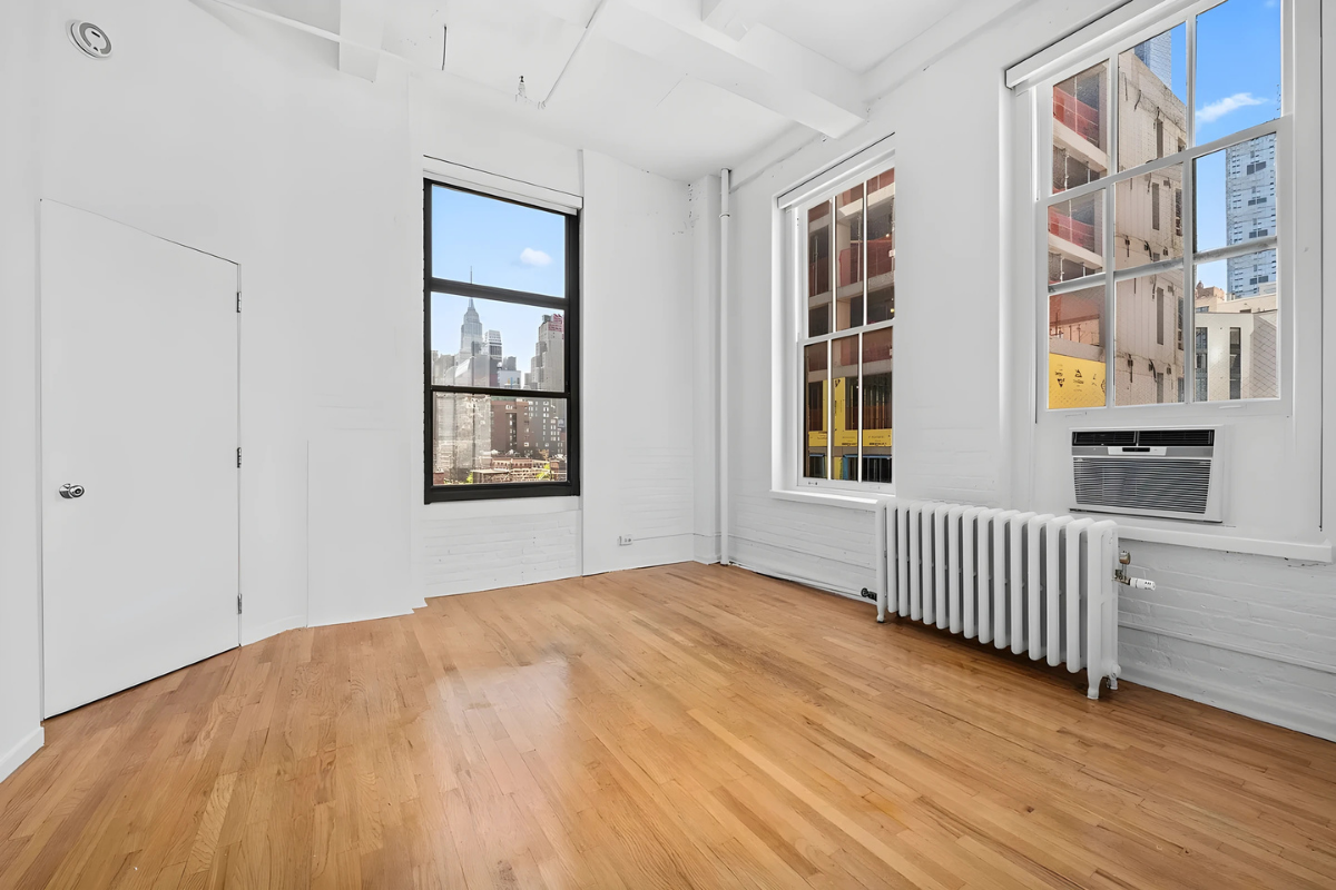 448 West 37th Street, Unit 6H Manhattan, NY 10018 - Photo 5 of 9 a view of an empty room with a window and wooden floor
