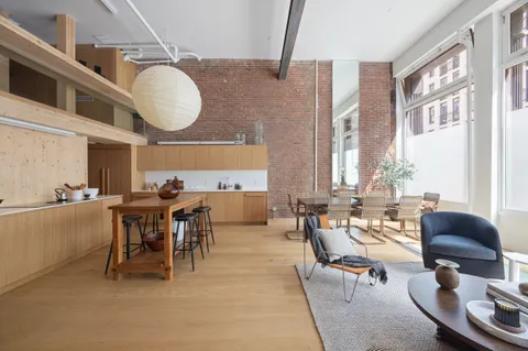 a living room with couches a large dining table and large window with wooden floor