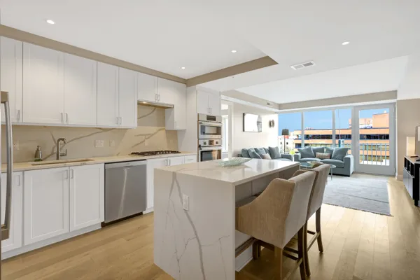 a kitchen with stainless steel appliances granite countertop a table chairs sink and cabinets
